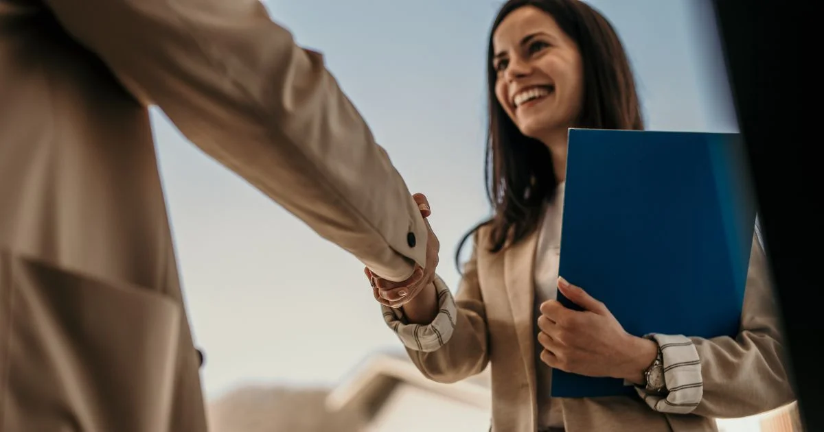 Smiling candidate shaking hands after successful interview.